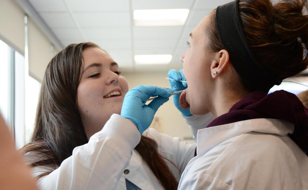 Student using tongue depressor on other student's mouth